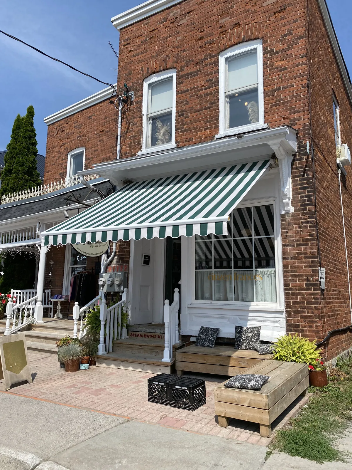 The red brick front of citizen frances with its green and white striped awning
